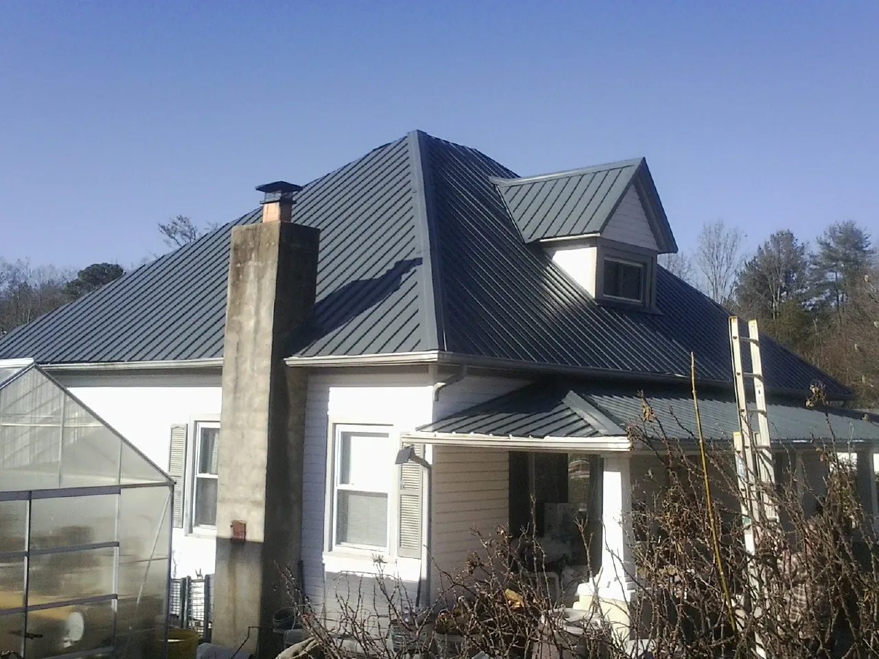Dark blue standing seam metal roof on a white farmhouse with dormer — Slate & Tile Roof Repair by Roofing Brothers in Blacksville