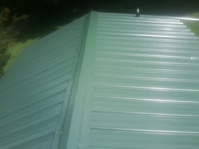 New green metal panels meeting at the ridge of a roof — Flat Roof Repair work by our crew in Blacksville