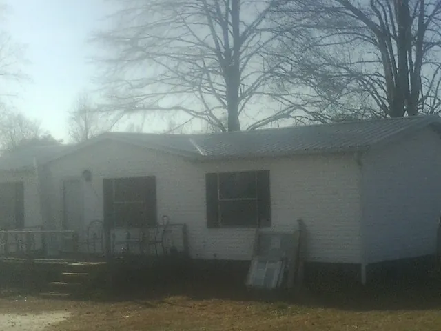 New metal roof on a white painted brick home on a foggy morning in Blacksville
