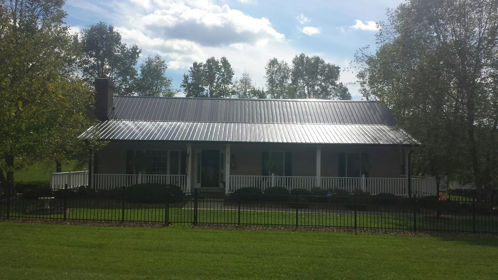 Gray metal roof on a brick ranch with a full width front porch — Gutter Guard Installation work by our crew in Blacksville