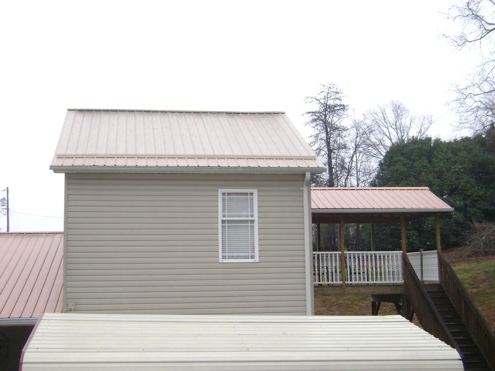 Tan metal roofs on a two story addition and attached porch, from a Roof Replacement job in Blacksville
