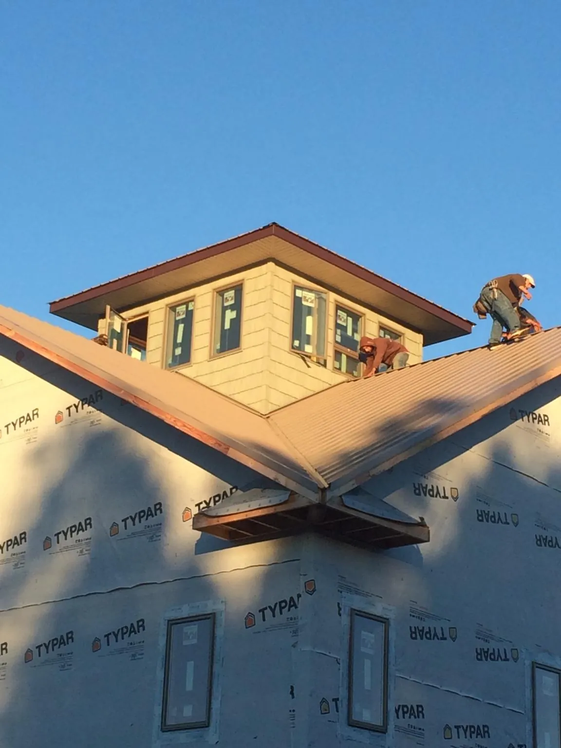 Roofers working around a rooftop cupola on a new metal roof at sunset — Roof Waterproofing in Blacksville by Roofing Brothers